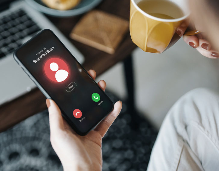 person looking at their mobile phone display that is showing an alert for an incoming suspected spam call