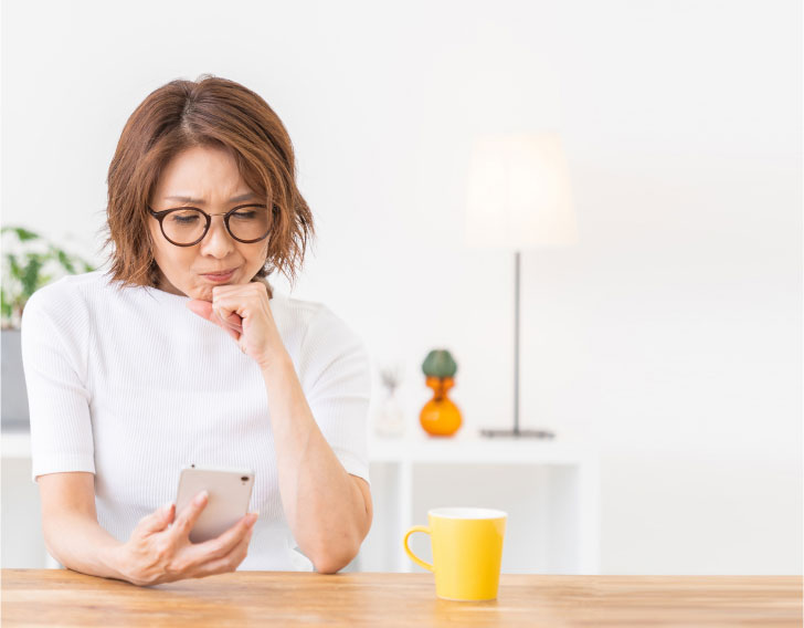 Person looking at their phone at a table with a confused facial expression