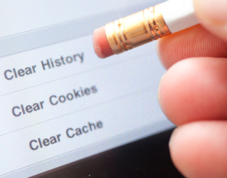 person pointing a pencil eraser at a screen that is asking to clear history, cookies, or cache